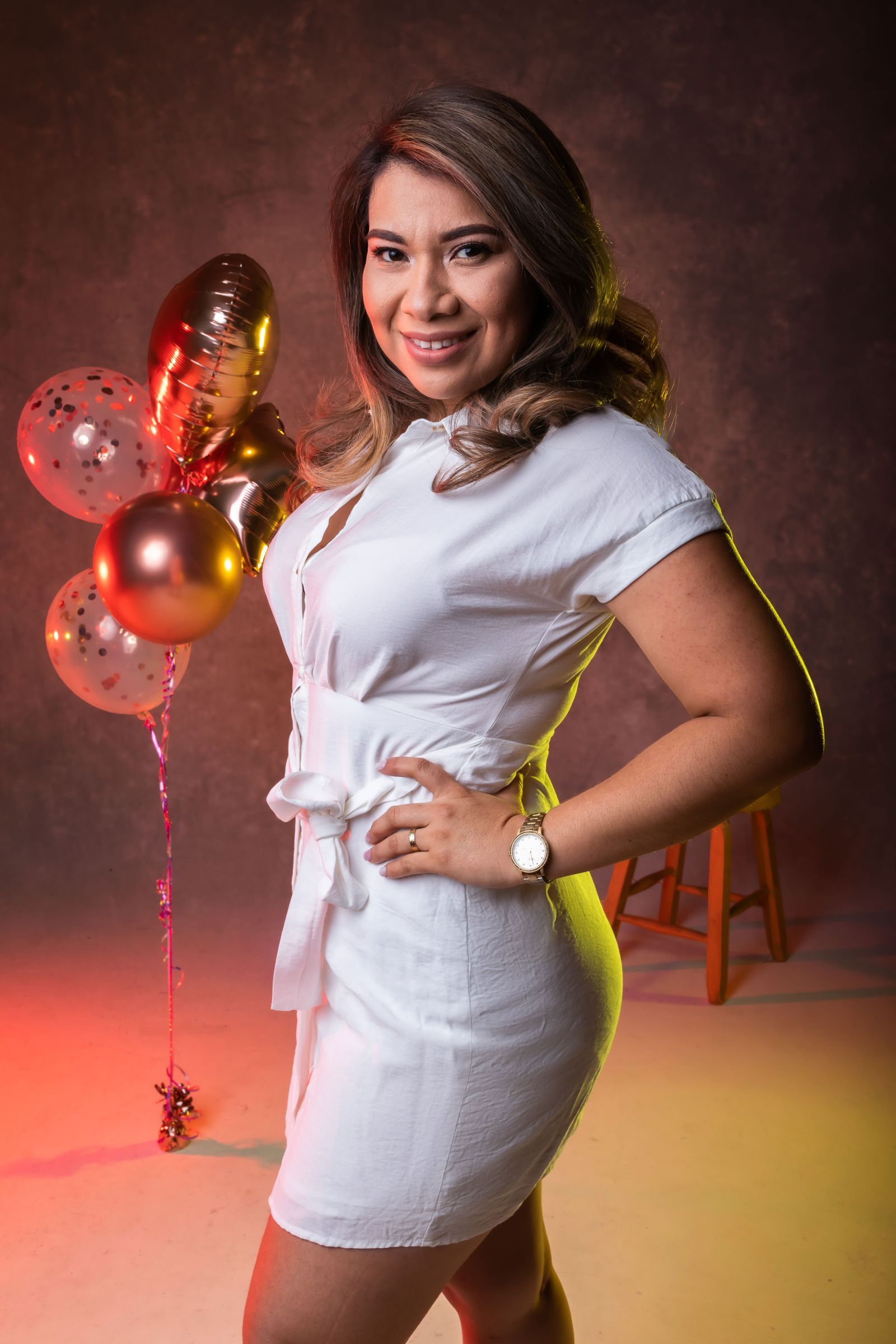 Smiling woman in a white dress posing with balloons in San Salvador